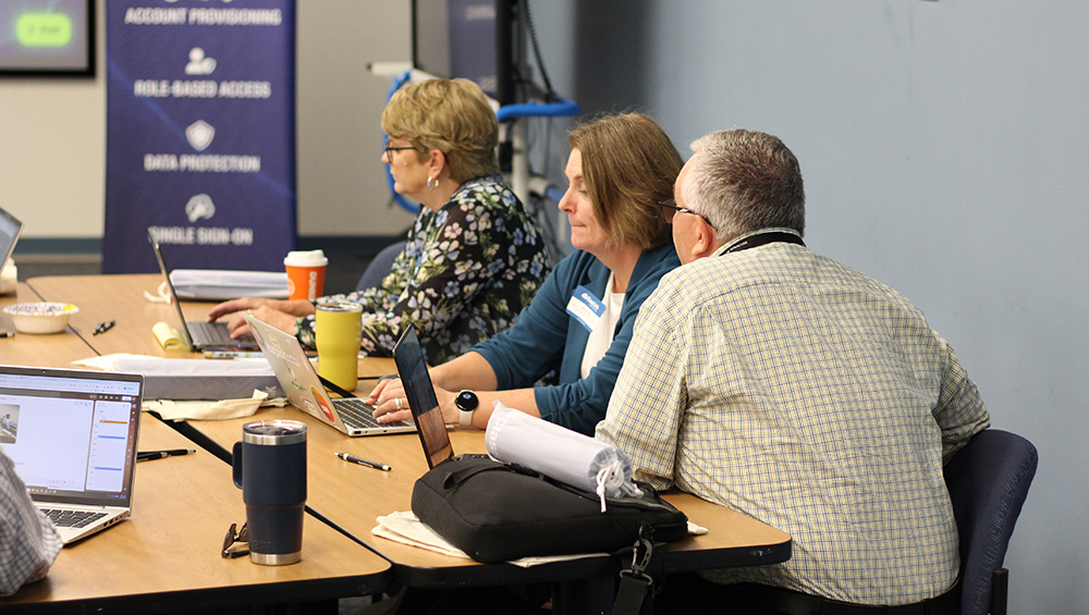 district attendees review data for their schools on a shared laptop